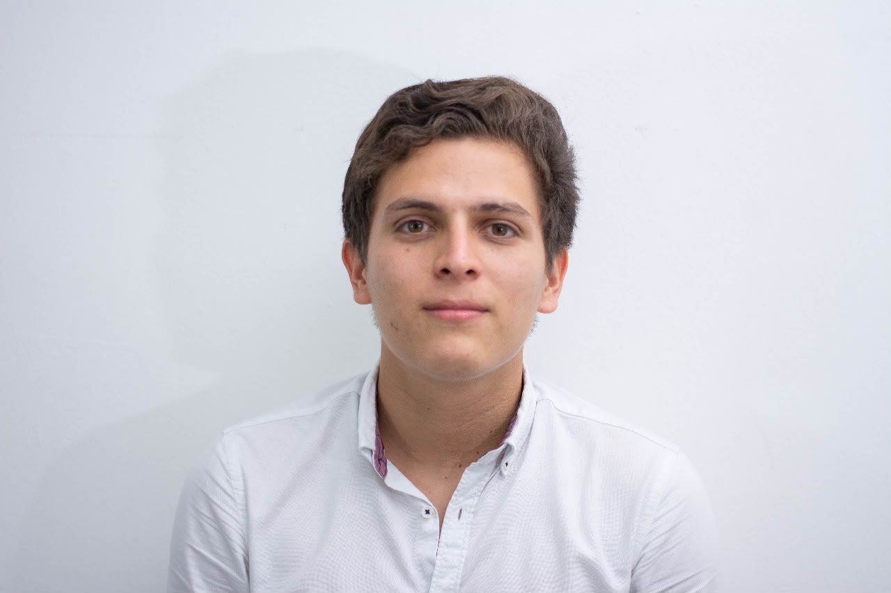 Young man with short hair wearing a white shirt, smiling against a plain white background for Xpert Elevator Service.