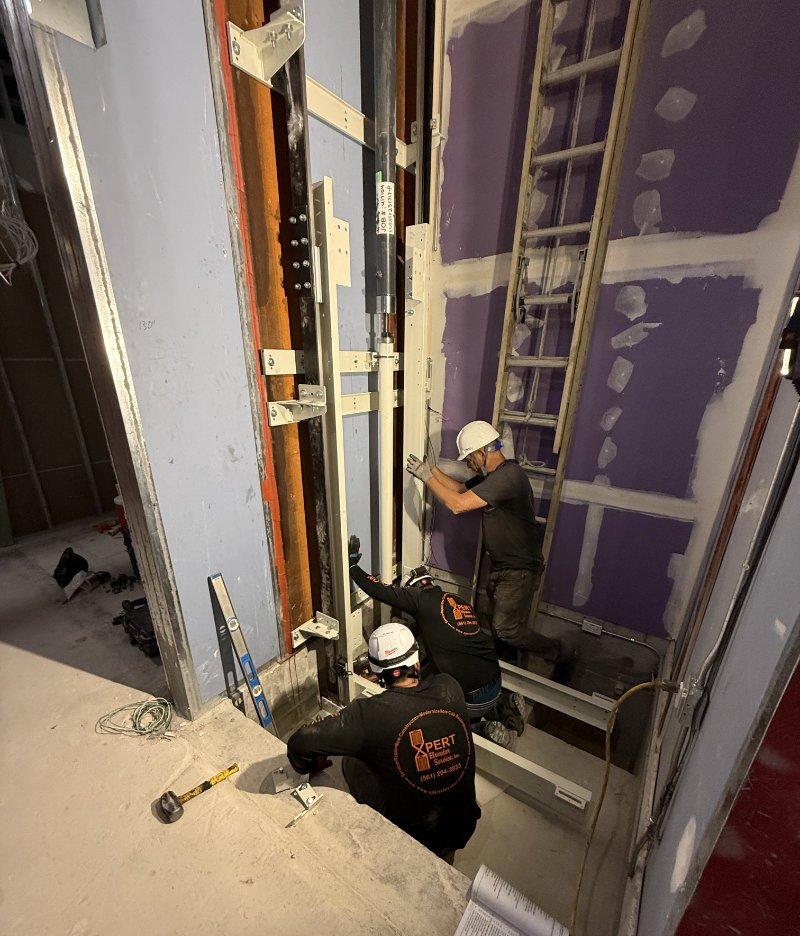Xpert Elevator Service technicians performing elevator repair work in a construction site.